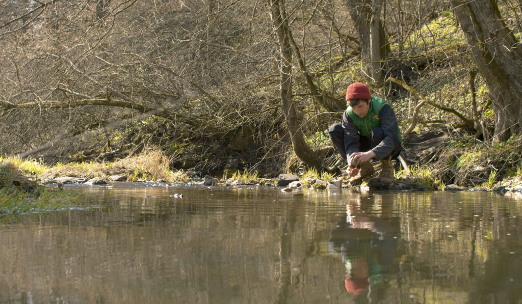 gift for outdoorsy kids: using a magnet fishing kit from the bank of a river